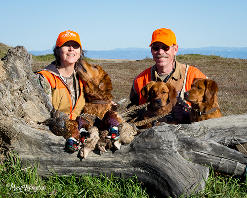 Mary and Tim with dogs after a pheasant hunt.